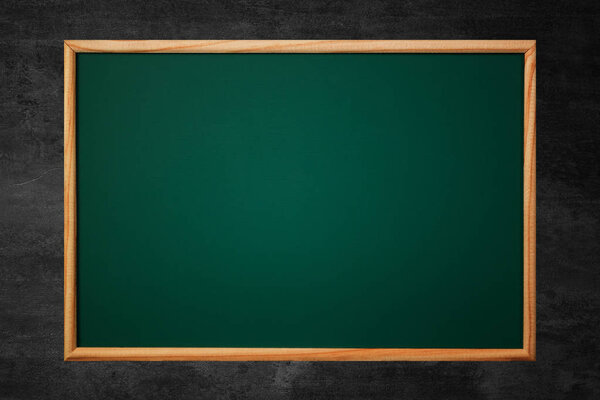 Empty green chalkboard or school board background and texture with wood frame on the black wall, education and back to school concept idea.