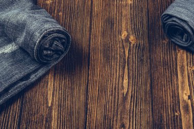 Frayed kot pantolon ya da kot denim koleksiyonu kaba koyu ahşap masa arka plan kopya alanı, eski moda stil kavramı ile rulo.