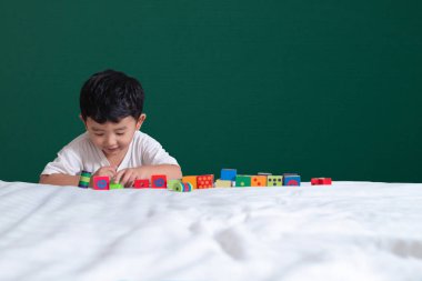 3 yaşında Asyalı çocuk oyun oyuncak ya da kare blok bulmaca yeşil kara tahta ya da okul yönetimi arka plan üzerinde çocuk yalan blok şekli veya parçalar, eğitim kavramı fikir oynayarak öğrenir.