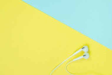 Sohbet tatlı mavi ve sarı renk pastel kağıt, üstten görünüm, doku ve arka plan üzerinde beyaz kulaklık veya kulak buds. müzik dinleme kavram fikir.