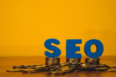 Ahşap çalışma masa, iş Seo arama motoru optimizasyonu kavramı ve sikke para yığını için SEO metin alfabe.