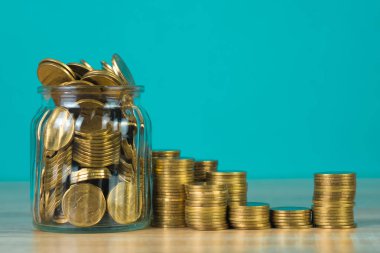 Madeni para yığınları ve altın sikke para cam kavanoz tablo kaydetme gelecekteki bankacılık finans için yeşil arka plana sahip konsept fikir.