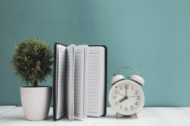 Ofis, banka donatımı veya office temel araçları öğelerini çalışma alanı, defter, çalar saat ve yeşil duvar arka plan kopya alanı ile küçük ağaç ahşap masa