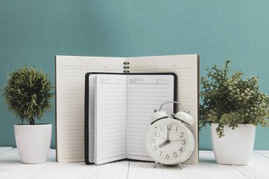 Ofis, banka donatımı veya office temel araçları öğelerini çalışma alanı, defter, çalar saat ve yeşil duvar arka plan kopya alanı ile küçük ağaç ahşap masa