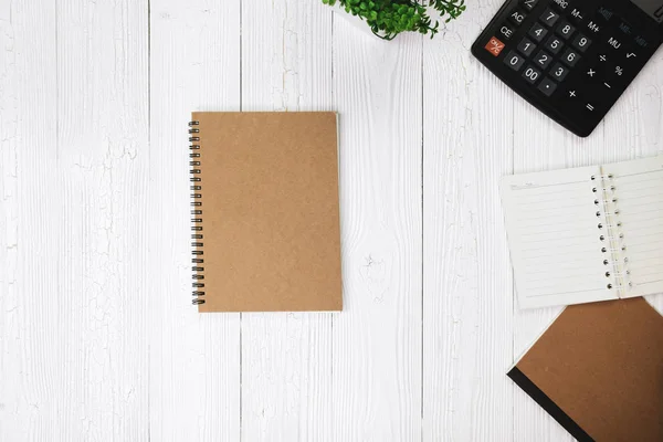 Fountain pen or ink pen with notebook paper and calculator on wooden working table with copy space, office desk concept idea. top view.