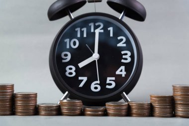 Çalar saat ve çalışma tablosu, tasarruf para kavramı, bankacılık ve iş kavramı fikri para yığınları basamakta.