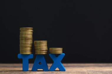 Vergi kavramı. Ahşap çalışma masa koyu arka plan, iş ve finansal kavram fikir para yığını ile vergi alfabesi.