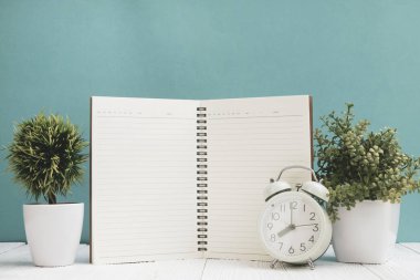 Ofis, banka donatımı veya office temel araçları öğelerini çalışma alanı, defter, çalar saat ve yeşil duvar arka plan kopya alanı ile küçük ağaç ahşap masa