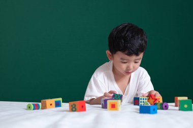 3 yaşında Asyalı çocuk oyun oyuncak ya da kare blok bulmaca yeşil kara tahta ya da okul yönetimi arka plan üzerinde çocuk yalan blok şekli veya parçalar, eğitim kavramı fikir oynayarak öğrenir.