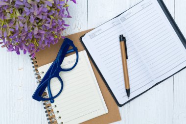Boş defter kağıt sayfası ve gözlük ile kalem ve ofis malzemeleri, üstten görünüm.