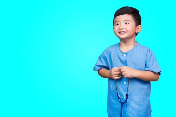 コピー スペース 健康概念のアイデアを持つ青い緑の背景にカメラを見て聴診器を持って青い医療制服姿で笑顔のアジア子供 — ストック写真