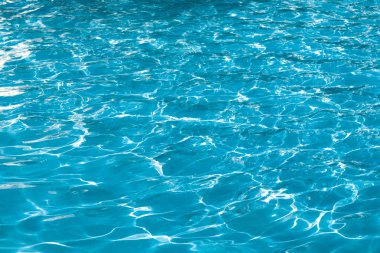 Mavi ve parlak dalgalanma temiz su yüzeyi güneş yansıması ile yüzme havuzunda.