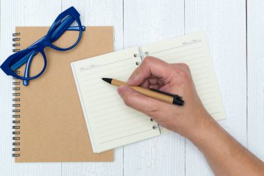 Adam el yazma, ahşap, gözlük ve ofis malzemeleri, üstten görünüm üzerinde kalem ile defter kağıt boş sayfa.