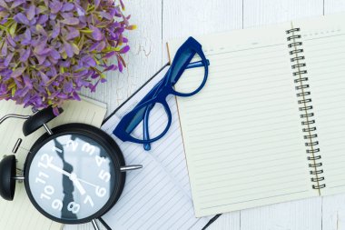 Boş defter kağıt sayfası ve gözlük ile kalem ve ofis malzemeleri, üstten görünüm.