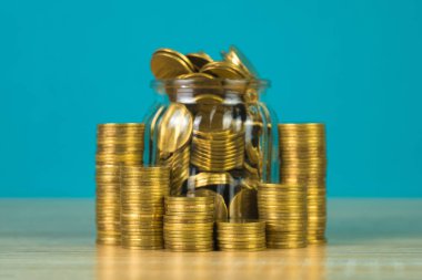 Madeni para yığınları ve altın sikke para cam kavanoz tablo kaydetme gelecekteki bankacılık finans için yeşil arka plana sahip konsept fikir.