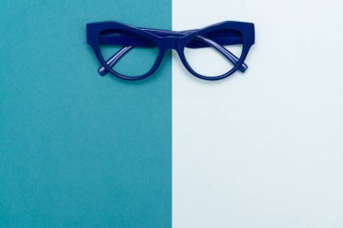 Üstten görünüm düz yatıyordu, modern mavi göz gözlük pastel Kağıt arka plan doku.