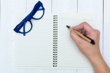 Adam el yazma, ahşap, gözlük ve ofis malzemeleri, üstten görünüm üzerinde kalem ile defter kağıt boş sayfa.