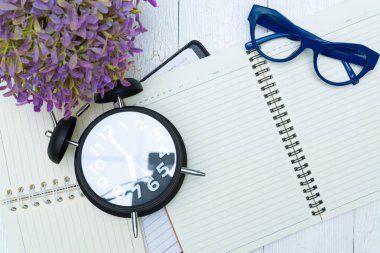 Boş defter kağıt sayfası ve gözlük ile kalem ve ofis malzemeleri, üstten görünüm.