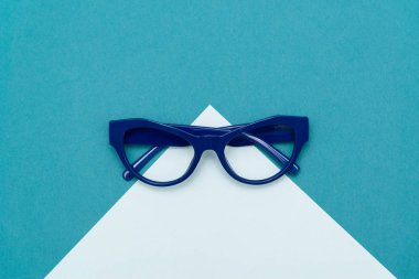Üstten görünüm düz yatıyordu, modern mavi göz gözlük pastel Kağıt arka plan doku.