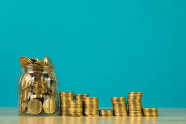 Madeni para yığınları ve altın sikke para cam kavanoz tablo kaydetme gelecekteki bankacılık finans için yeşil arka plana sahip konsept fikir.