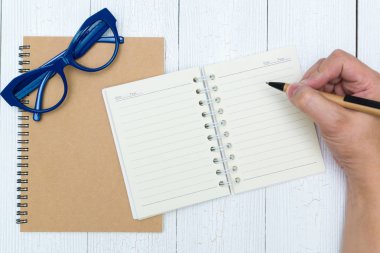 Adam el yazma, ahşap, gözlük ve ofis malzemeleri, üstten görünüm üzerinde kalem ile defter kağıt boş sayfa.