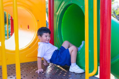 Asyalı çocuk bahçesi yaz, mutlu çocuk anaokulu veya okul öncesi okul bahçesinde ışığında altında slayt oynayan.
