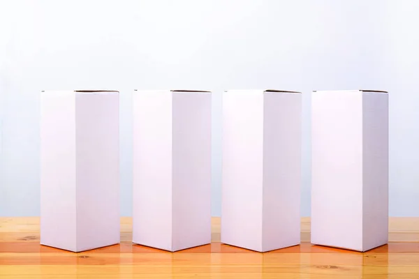 Vier Packungen weißer Karton für lange Gegenstände auf Holz leer — Stockfoto