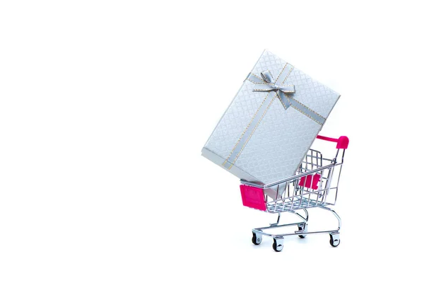 White gift box with ribbon bow and shopping cart or supermarket — Stock Photo, Image