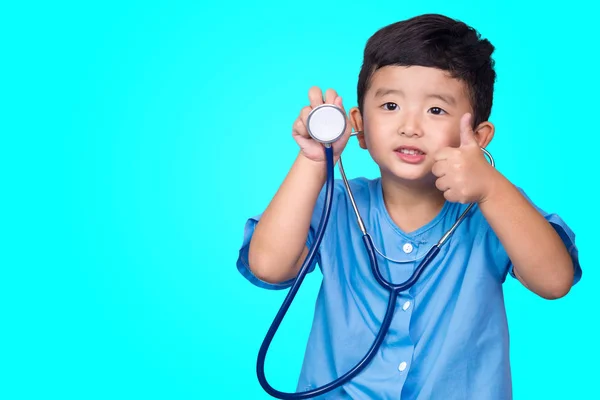 Sonriente niño asiático en uniforme médico azul celebración estetoscopio lo — Foto de Stock