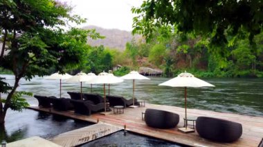 Güverte sandalye veya nehir Kwai Kanchanaburi, Tayland yakın Resort sahil sal üzerinde Divan ve şemsiyeler. seyahat ve tatil Tayland