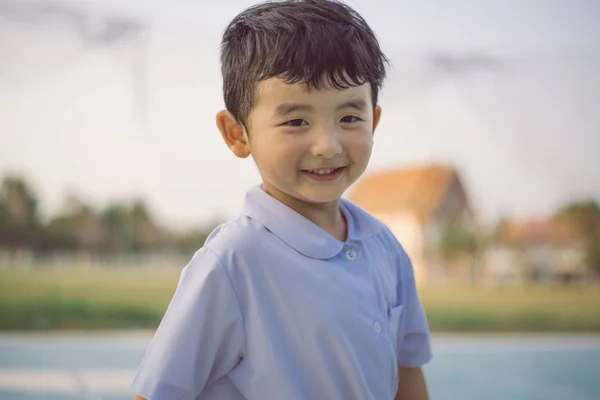 Retrato al aire libre de un niño estudiante asiático feliz en uniforme escolar — Foto de Stock