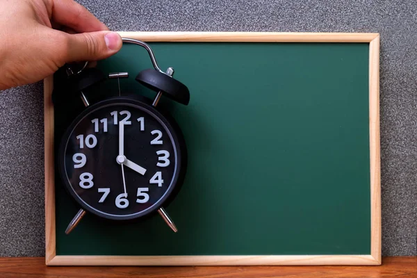 Relógio de alarme vintage preto na mão com quadro verde, cópia sp — Fotografia de Stock