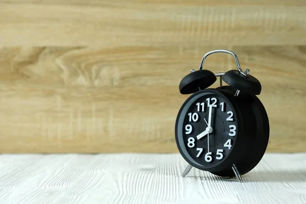 Relógio de alarme retro preto na mesa de madeira, conceito de tempo . — Fotografia de Stock