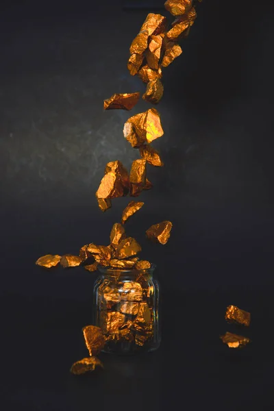 Spada bryłki złota lub rudy złota i szklany słoik w ciemnym pomieszczeniu — Zdjęcie stockowe