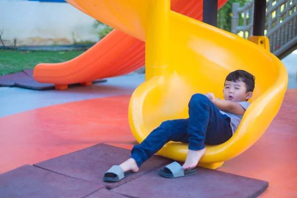 Asiático niño jugando diapositiva en el parque infantil bajo la luz del sol en — Foto de Stock