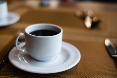 Kahvaltı için restoranda yemek masasında sıcak kahve fincanı.