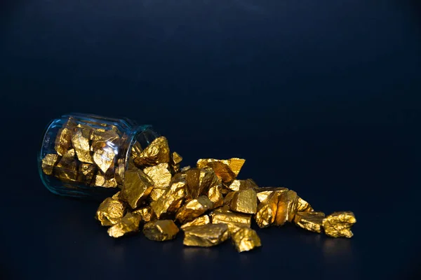 Gold nuggets or gold ore and glass jar in dark room.