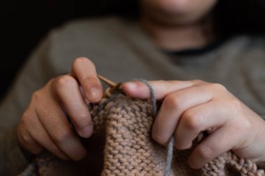 Örgü şişlerini tutan bir elin yakın çekimi.