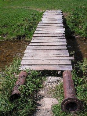 Metal borular ve ahşap tahtalardan yapılmış kendi kendine yapılmış köprü.