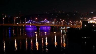 Gece aydınlatma köprüde, ışıklı yansıtan cityscape, köprü, gece zaman atlamalı sahne ışıkları gece güzel Köprü Nehri Dnepr Kiev yaya köprüsü güzel gece yaktı ve suya yansıyan
