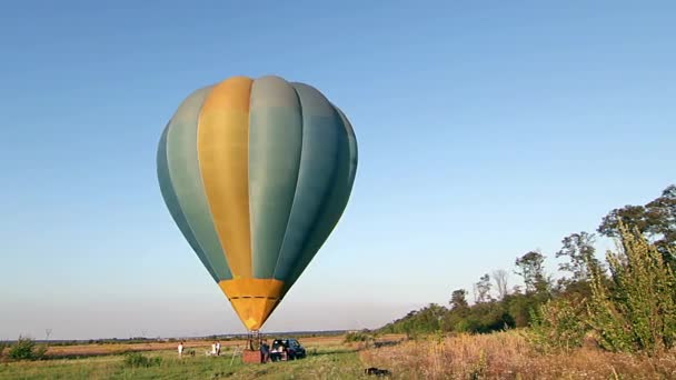 空気バルーン開始 日没時間の経過で離陸 熱気球は夏夕日 夏の夜に人々 を持つフィールドで気球で飛ぶ草フィールドから — ストック動画
