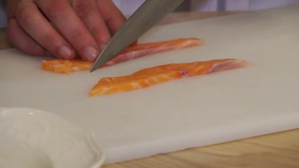 サーモンの切り身 サーモンの切り身 魚のナイフ切り サーモンの食欲をそそる 寿司バーのキッチンに立つシェフサーモンの切り身 サーモンの切り身 — ストック動画