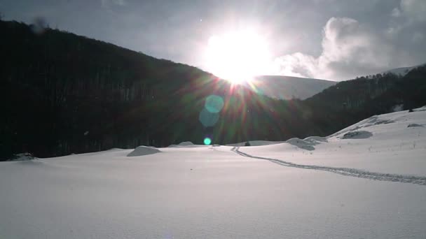 太陽や冬の山 冬の山の小道の斜面 冬山のスローモーションで雪冬景色 雪の上の足跡 — ストック動画