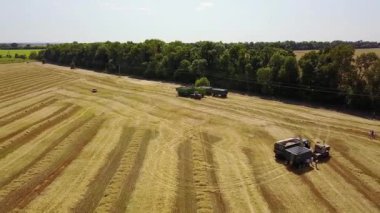 buğday tarlasında tarım makinelerinin havadan görünümü, kırsal kesimde tarım makineleri ile tarım sahnesi, tarlada birleşerek hasat makinesi ve traktör ve römork üzerinde uçan havadan görünüm