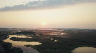 Güneşin doğuşundaki sabah sisinin havadan görünüşü, nehirdeki sabah sisinin içinden geçen turuncu güneş ışınları, gün doğumunda sisli mistik nehrin havadan görünüşü.
