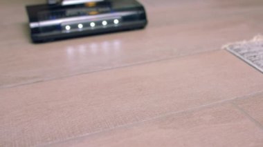 Döşemeleri süpürüp, yerleri süpürüp, evi temizleyip, kanepenin altını süpürüp, zemini yavaş çekimde süpürüyor.