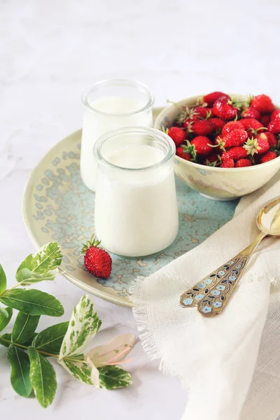 Sağlıklı süt tatlı: taze yoğurt, süt ve yabani çilek iki kavanoz