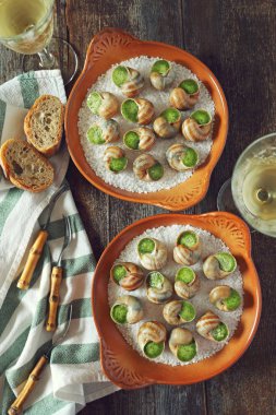 Escargots, geleneksel Fransız mutfağı: salyangoz sos Bordo ve bir bardak beyaz şarap. Üstten görünüm, tonlu görüntü