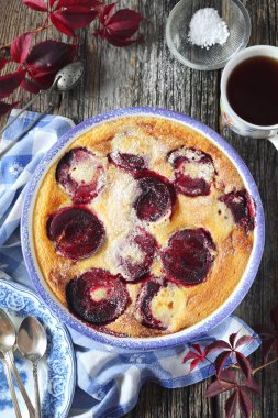 Sonbahar tatlı. Bir kahve şeker sos, krema, kırmızı erik clafoutis ve Fransız mutfağı. Ahşap arka plan üzerinde üstten görünüm