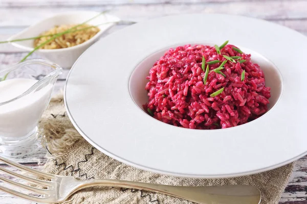Diet food. Pink rice. Beetroot risotto from brown rice with almond milk, chives onion dressing
